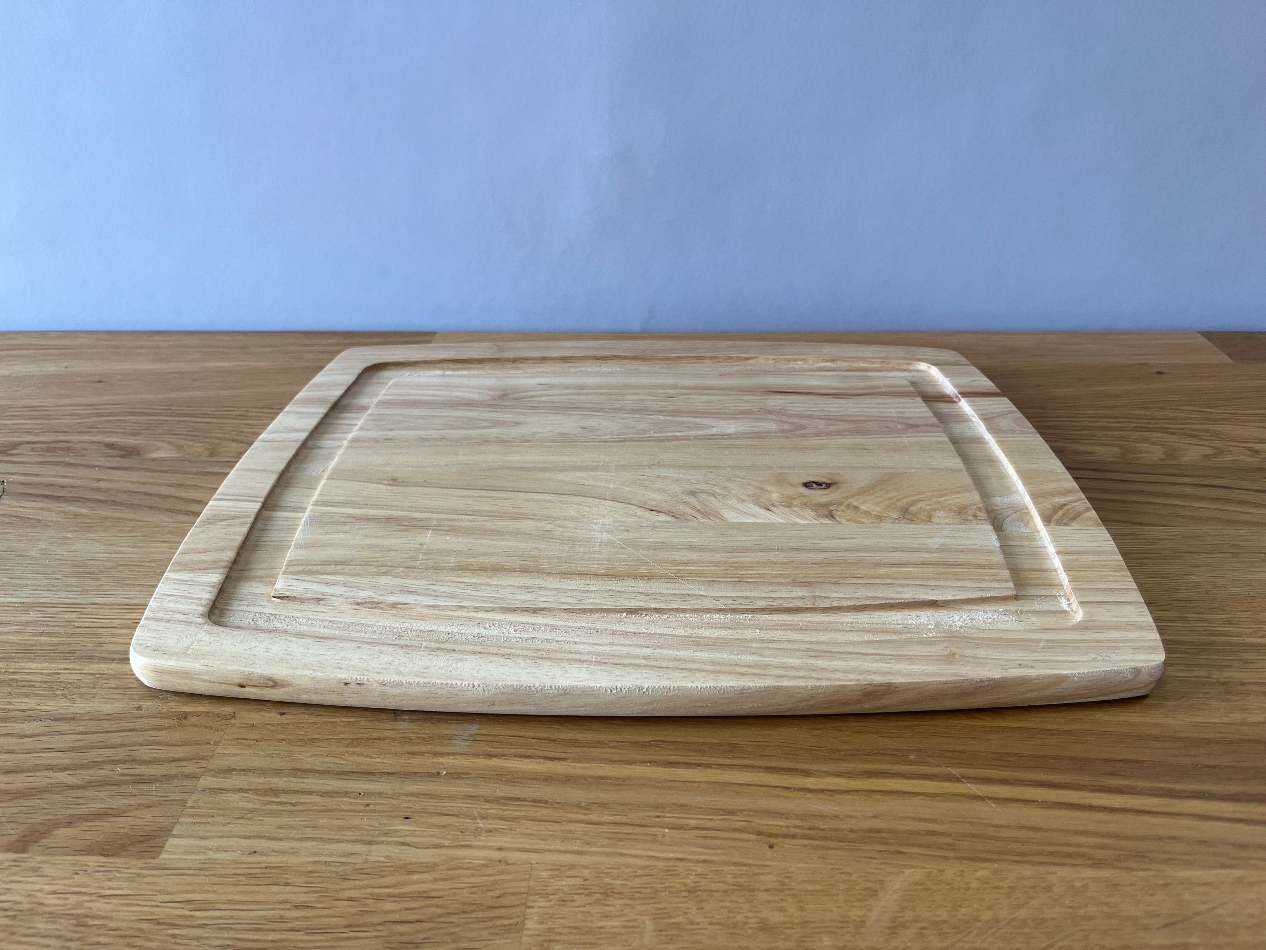 light wood cutting board with indent around it