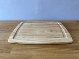 light wood cutting board with indent around it