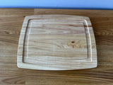 light wood cutting board with indent around it